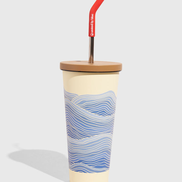 Eggshell - Waves 24 oz Insulated Steel Straw Tumbler (Angle): Cream tumbler with blue wave print, tan lid, red-tipped metal straw