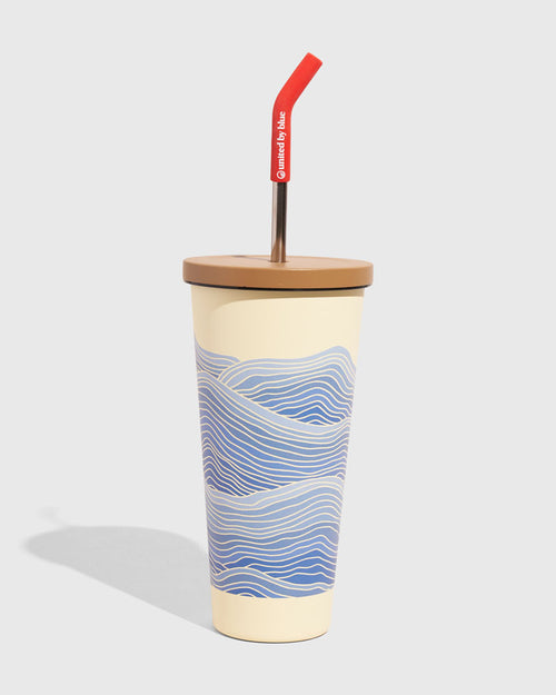 Eggshell - Waves 24 oz Insulated Steel Straw Tumbler (Angle): Cream tumbler with blue wave print, tan lid, red-tipped metal straw