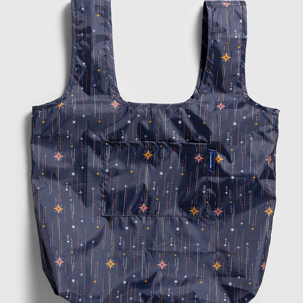 Obsidian The Packable Tote (Flat-lay): Dark navy tote with star and sparkle print, two handles, front pocket