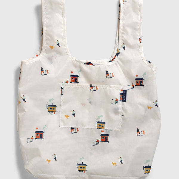 Tusk The Packable Tote (Flat-lay): White tote with small ice fishing hut and dog repeat print, front pocket
