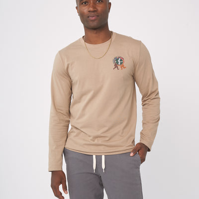 Ash Earth Circle - Long-Sleeve Graphic Tee (In-use): Man wearing tan long-sleeve tee with small globe graphic on chest