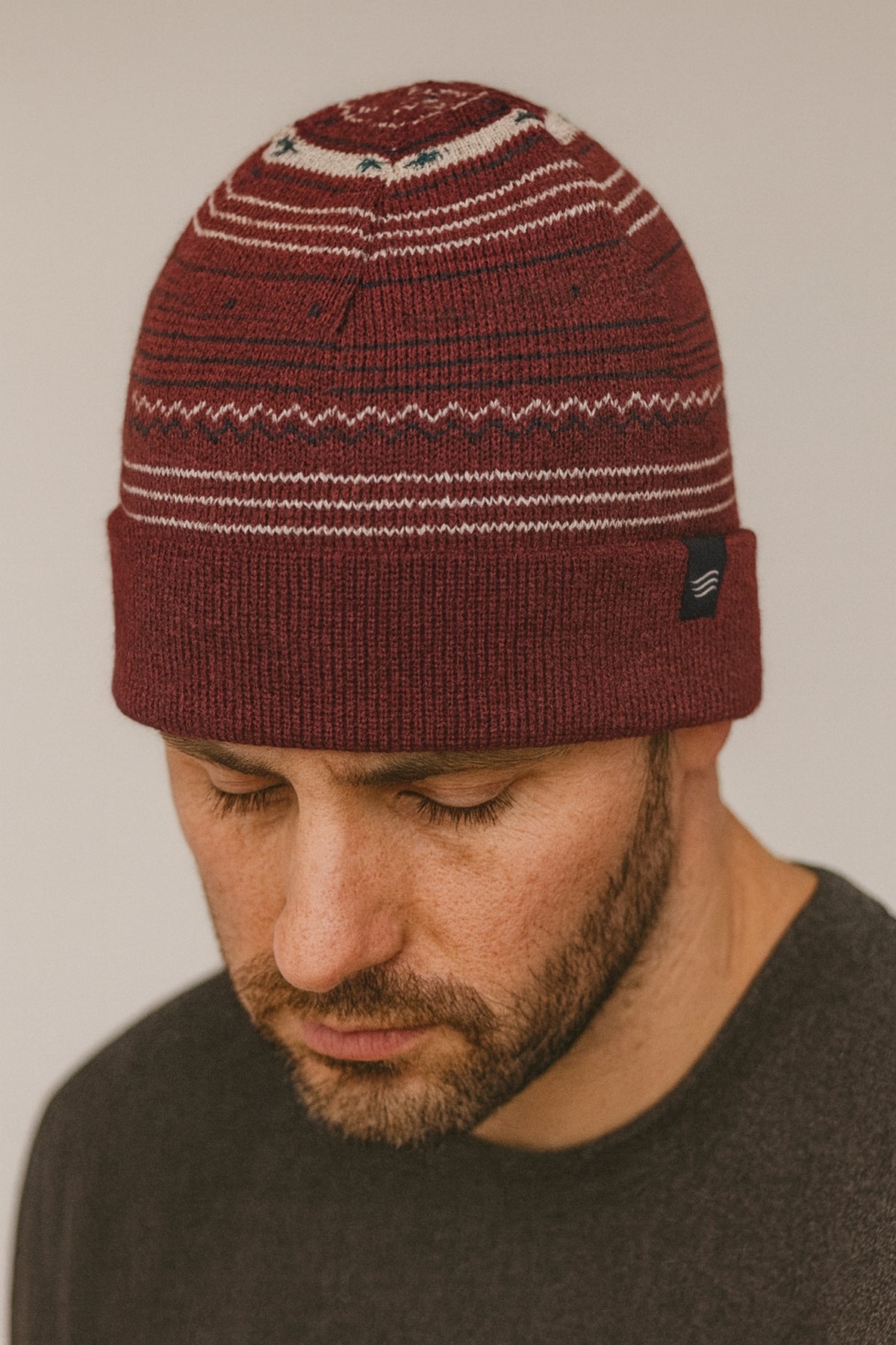 Burgundy Multi Merino Wool Modern Fair Isle Knit Beanie (In-use): Man wearing dark red Fair Isle knit beanie with white patterned stripes