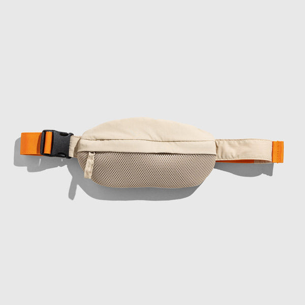 Sand (Re)active™ 1L Fanny Pack (Flat-lay): Beige fanny pack with mesh pocket and orange adjustable strap buckle