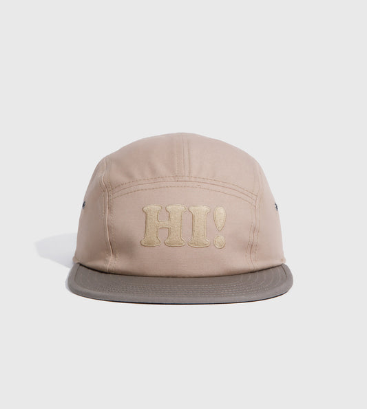 Tan Hi Organic 5-Panel Hat (Angle): Five-panel cap in tan with embroidered 'HI!' text on front panel
