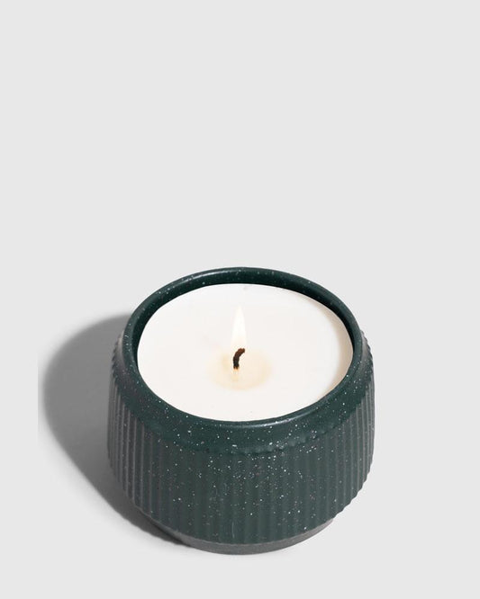DARK GREEN 14 oz. Ceramic Keepsake Candle - Tioga Woods (Angle): Small dark teal ribbed ceramic vessel holds white wax with lit wick