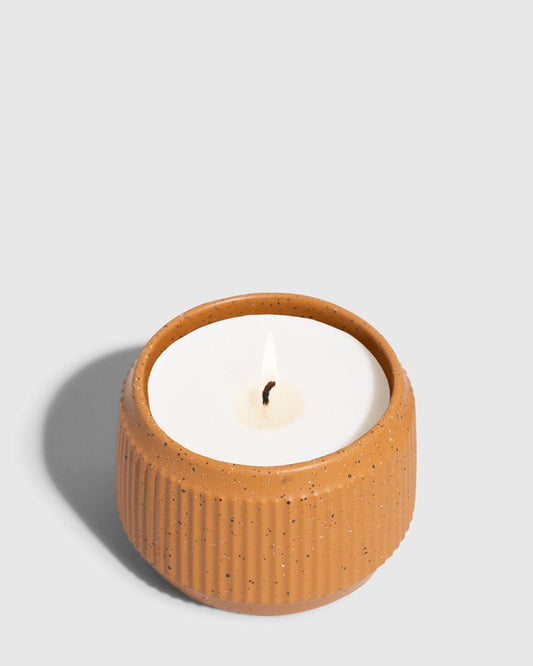 CARAMEL 14 oz. Ceramic Keepsake Candle - Mountain Peak (Angle): Round ribbed speckled terracotta ceramic vessel holding white wax candle, lit wick