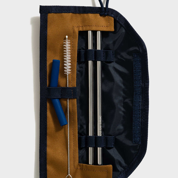 Camel The Straw Kit (Flat-lay): Open navy roll revealing two steel straws, blue silicone tip, and cleaning brush