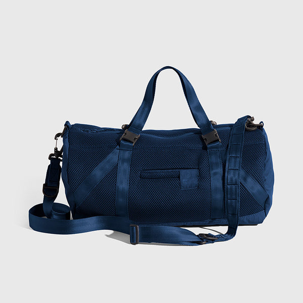 Blueberry (Re)active™ 16L Mini Duffle (Angle): Navy blue mesh duffle with top handles, crossbody strap, and buckle straps