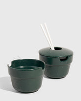 Pine Stoneware Stackable Noodle Bowl Set (Angle): Two dark green speckled stoneware bowls, one lidded with white chopsticks inserted