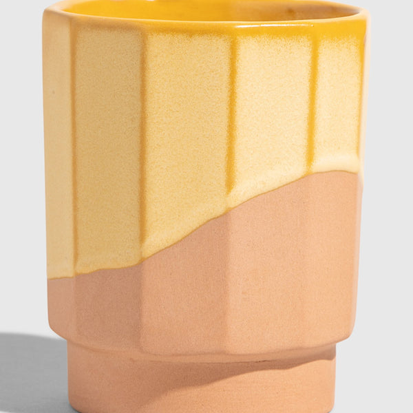 Honey 8 oz. Stackable Stoneware Tumbler (Angle): Faceted stoneware tumbler with yellow glaze dripping over unglazed terracotta base