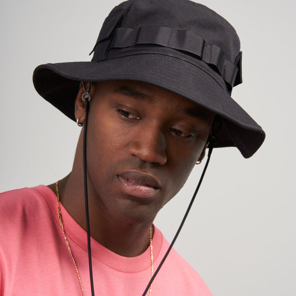 Obsidian Organic Bucket Stash Hat (In-use): Dark bucket hat with webbing band and chin cord, worn by man