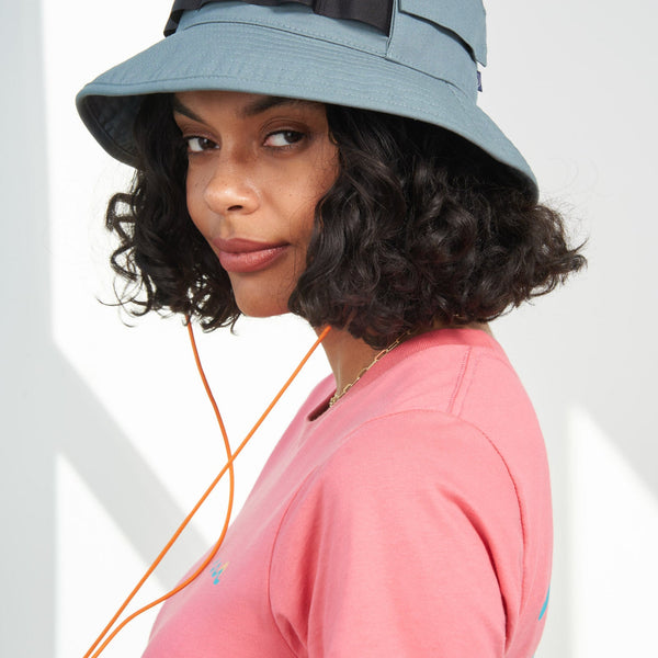 Sky Blue Organic Bucket Stash Hat (In-use): Woman wearing light blue bucket hat with black webbing band and orange chin cord