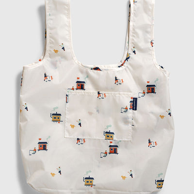 Tusk The Packable Tote (Flat-lay): White tote with small ice fishing hut and dog print, front pocket visible