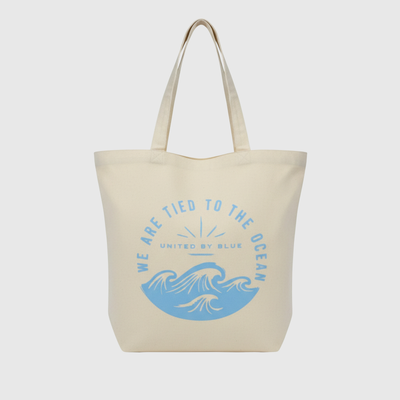 We Are Tied To The Ocean My Favorite Daily Tote (Front): Cream canvas tote with blue ocean waves and arched text graphic
