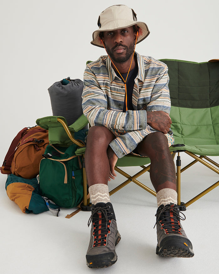 NATURAL / KHAKI UTILITY BUCKET HAT (In-use): Man wearing cream bucket hat seated on green camping chair outdoors