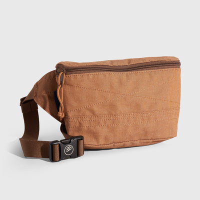 Camel Deadstock (R)evolution™ Canvas Fanny Pack (Angle): Tan canvas belt bag with brown zipper, stitching details, and buckle strap