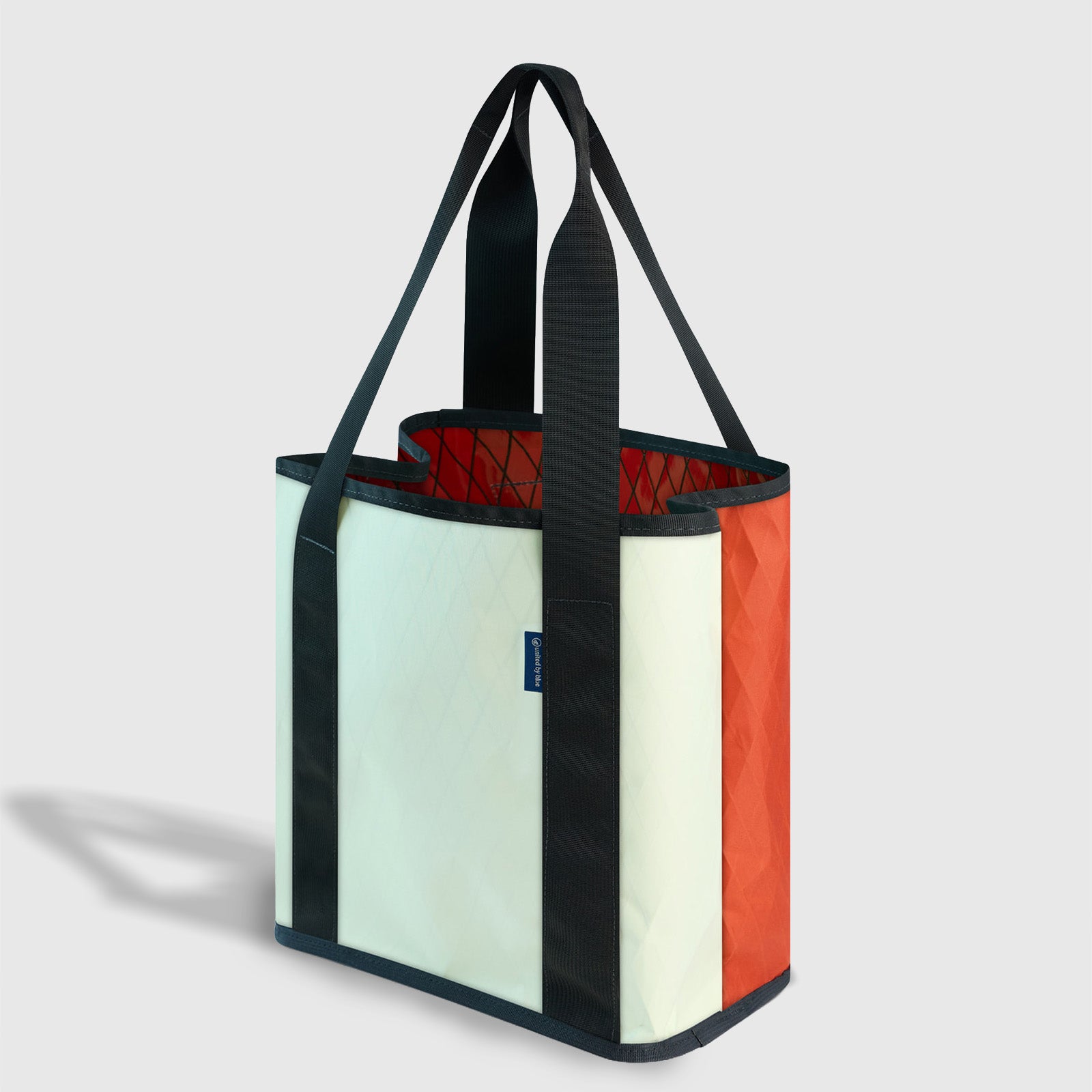 Coyote Coral The Westward Tote (Angle): Mint and coral tote with dark trim, open top, black handles