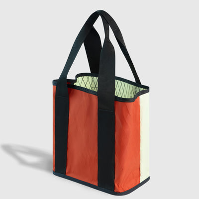 Coyote Coral The Westward Tote (Angle): Open rust-orange and cream tote with dark green straps and lime interior