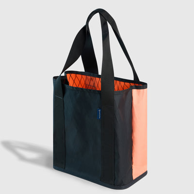 Peach-Navy The Westward Tote (Angle): Dark teal and peach tote with black straps and orange mesh interior visible
