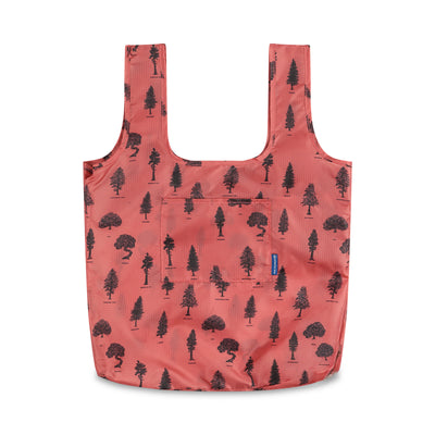 Clay The Packable Tote (Front): Coral red tote with dark tree silhouettes print, two straps, front pocket