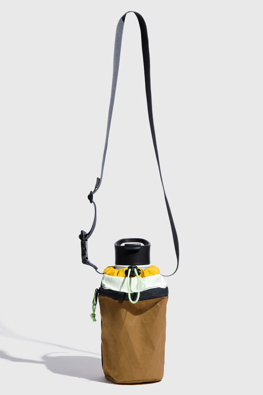 Brown bag with a drawstring and black strap on a light gray background