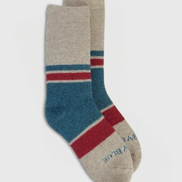 Pair of socks with blue, red, and beige stripes on a light gray background
