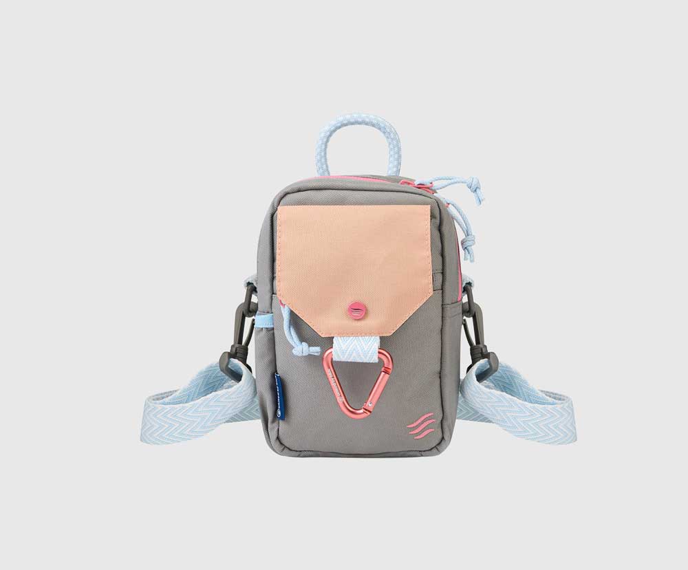 Lt Grey (R)evolution Daily Cross Body (Front): Grey crossbody bag with peach snap-flap pocket, pink carabiner, blue rope handle, chevron strap