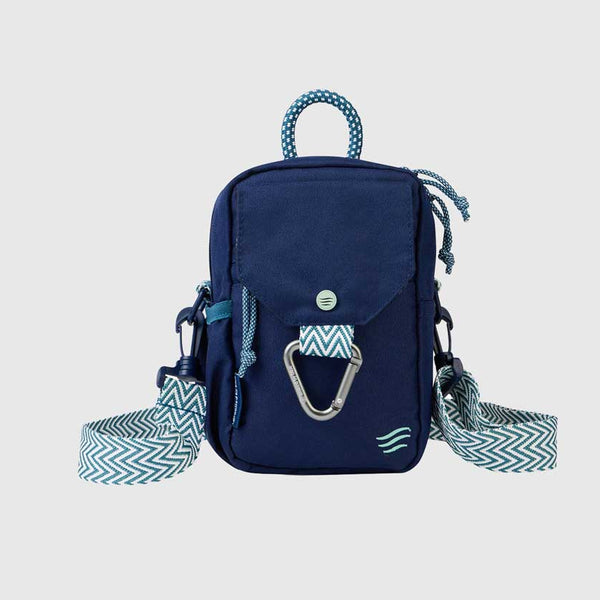 Navy (R)evolution Daily Cross Body (Front): Navy crossbody bag with mint accents, silver carabiner, snap-flap pocket, and zigzag chevron strap