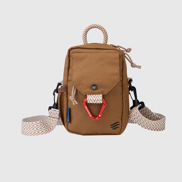 Tigers Eye (R)evolution Daily Cross Body (Front): Tan brown crossbody bag with snap-flap pocket, red carabiner, rope handle, and chevron strap