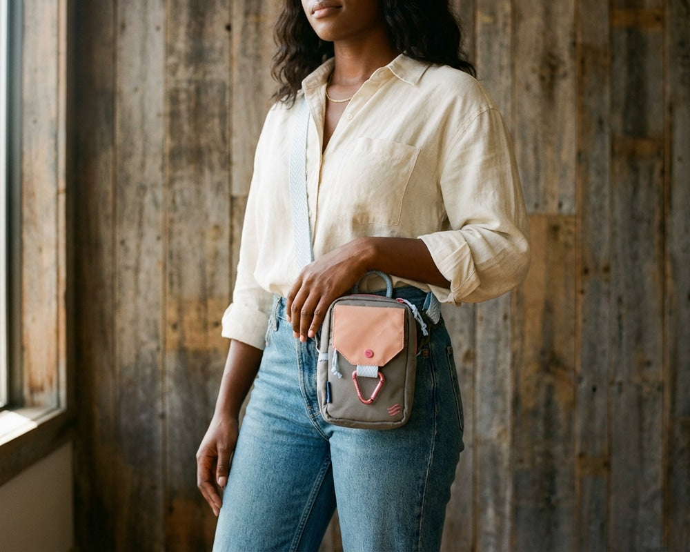 Lt Grey (R)evolution™ Daily Cross Body (In-use): Woman wearing olive crossbody bag with peach flap and carabiner clip