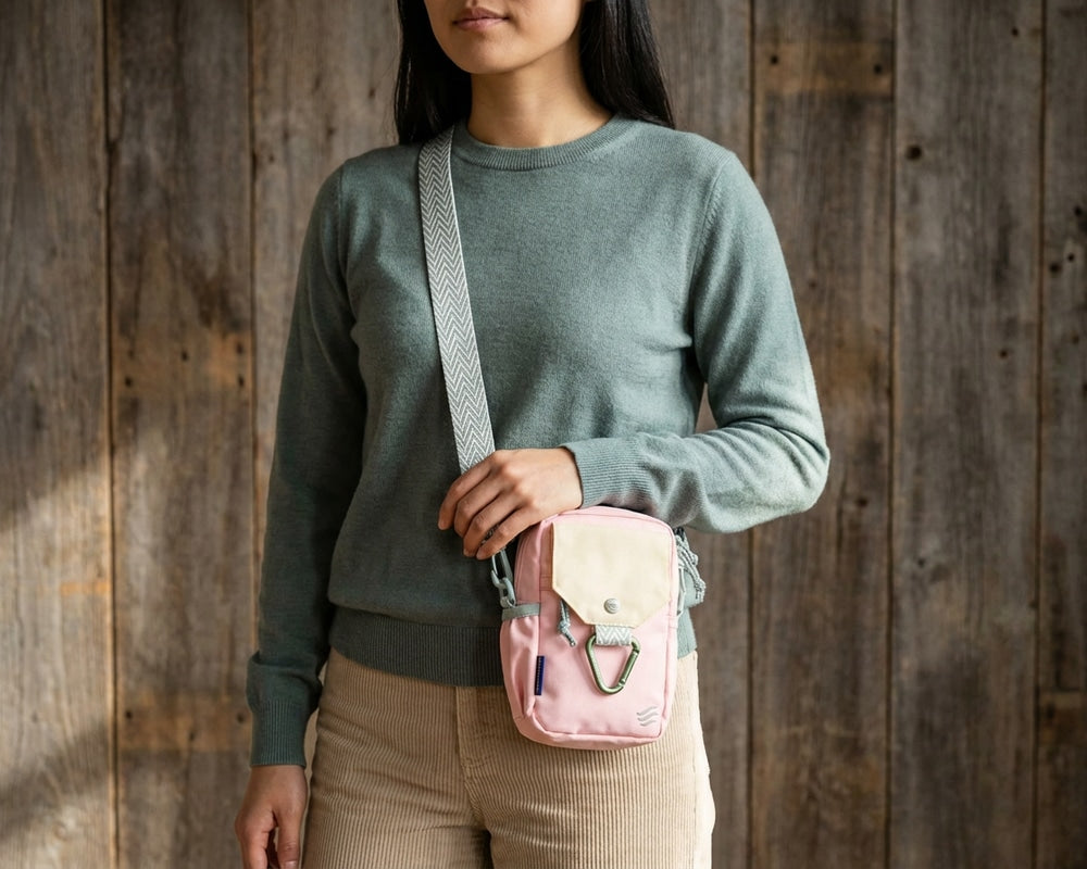 Lt Pink Bag - Person wearing a green sweater and beige pants with a pink crossbody bag against a wooden background