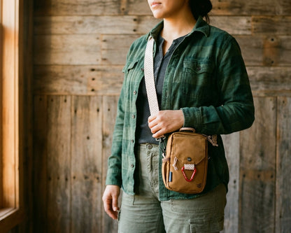 Tigers Eye Bag - Person wearing a green jacket holding a brown crossbody bag against a wooden wall.