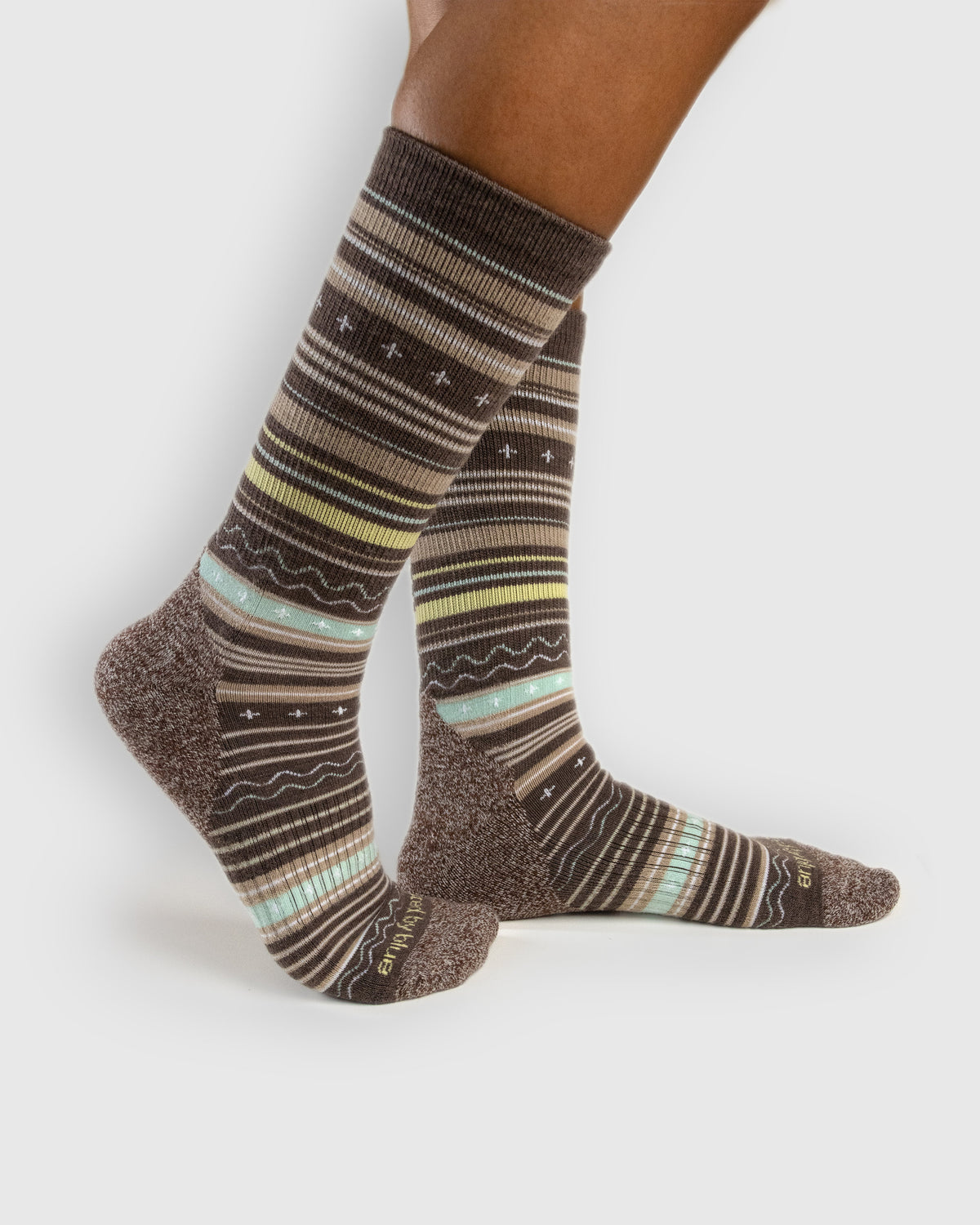 Brown Hthr Merino Wool Trail Crew Sock - New Color (In-use): Brown striped merino crew socks worn on feet, side view