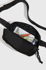 Black (Re)volution™ 1L Go-Anywhere Bag (Detail): Black fanny pack open, showing glasses, keys, phone, and orange pen inside