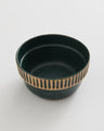 Pine Stoneware Stackable Bowl (Angle): Dark green speckled bowl with tan carved stripe pattern around exterior