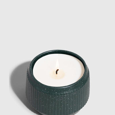 DARK GREEN 14 oz. Ceramic Keepsake Candle - Tioga Woods (Angle): Small dark teal ribbed ceramic vessel holds white wax with lit wick