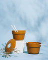 Caramel Stoneware Stackable Noodle Bowl Set (Angle): Two speckled amber bowls with ridged bases, white straws, donut lid