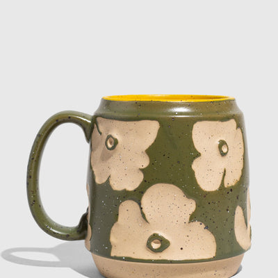 Forest Floor 16 oz. Stoneware Mug (Angle): Green speckled stoneware mug with cream floral relief pattern and yellow interior