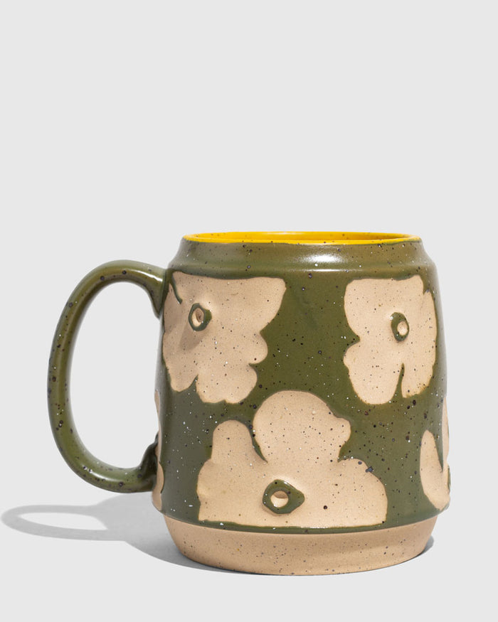 Forest Floor 16 oz. Stoneware Mug (Angle): Green speckled stoneware mug with cream floral relief pattern and yellow interior