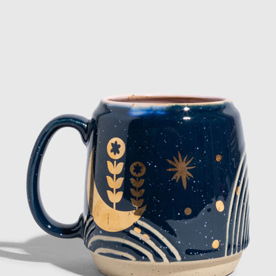 Nightfall Blue 16 oz. Stoneware Mug (Angle): Navy blue stoneware mug with gold moon, botanicals, and star motifs