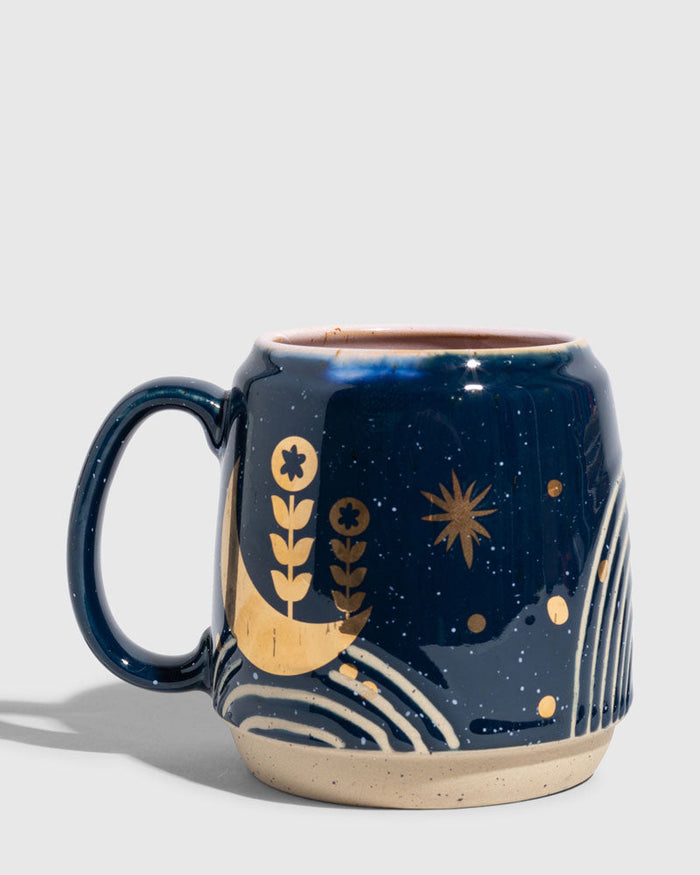 Nightfall Blue 16 oz. Stoneware Mug (Angle): Navy blue stoneware mug with gold moon, botanicals, and star motifs