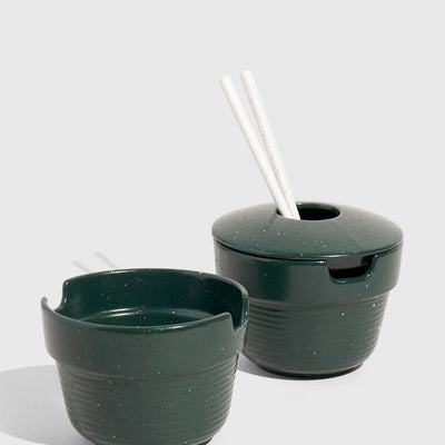 Pine Stoneware Stackable Noodle Bowl Set (Angle): Two dark green speckled stoneware bowls, one lidded with white chopsticks inserted