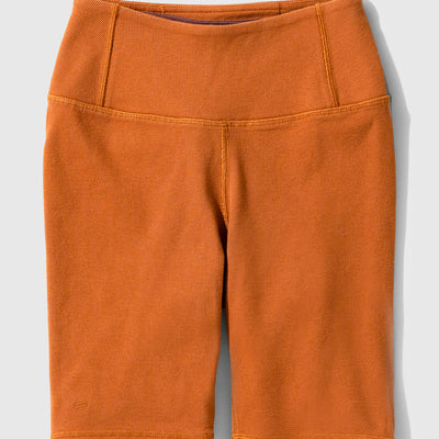 Cinnamon EcoKnit™ Ribbed Bike Short (Flat-lay): Burnt orange ribbed bike shorts with wide waistband and seam detailing