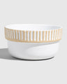 Eggshell Stoneware Stackable Bowl (Angle): Round white speckled bowl with tan carved vertical stripe band near rim